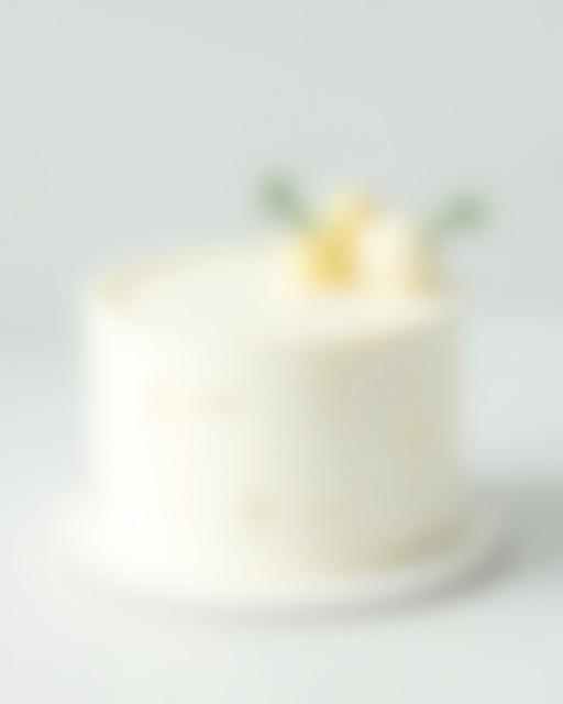 En minimalistisk festkake med en glatt, hvit glasur, dekorert med subtile gull-detaljer og en enkel grønn kvist.